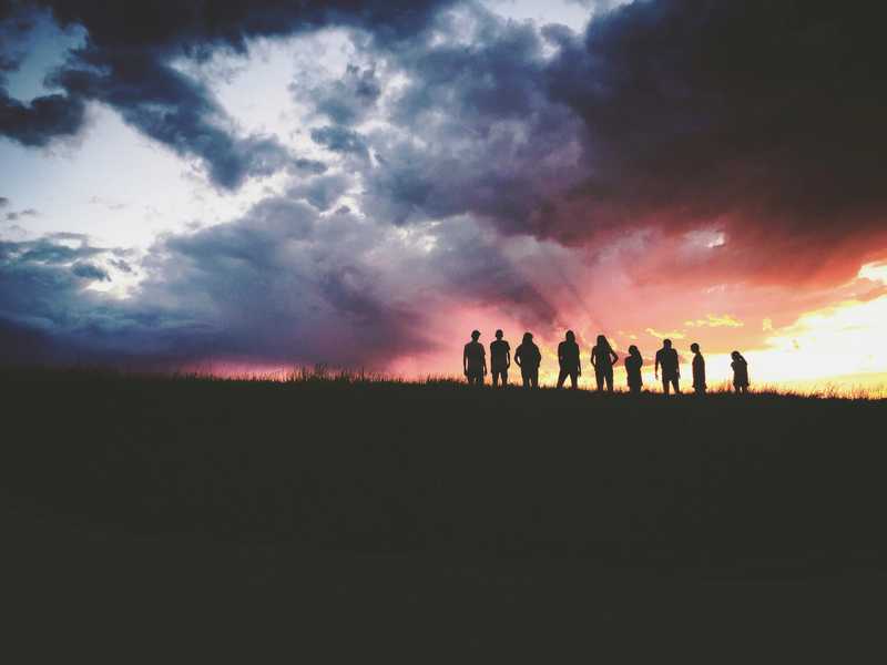 A team of people standing against a sunset https://unsplash.com/@hudsonhintze